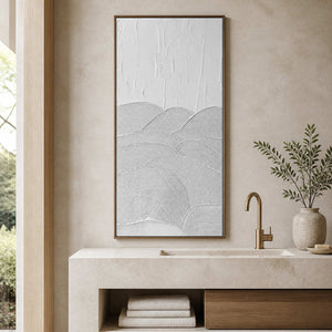 Wood framed white textured artwork above a pale stone bathroom vanity.