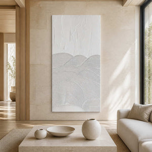 Frameless white textured artwork beside neutral seating in a sunlit living room.