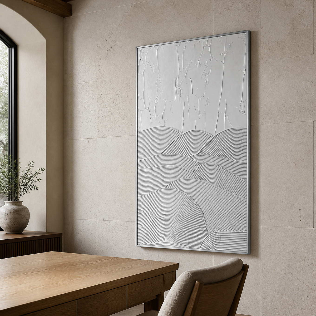 Silver framed white grooved artwork beside a wooden desk in a bright study.