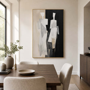Gold framed minimalist figurative painting beside a wooden table in a bright dining room.