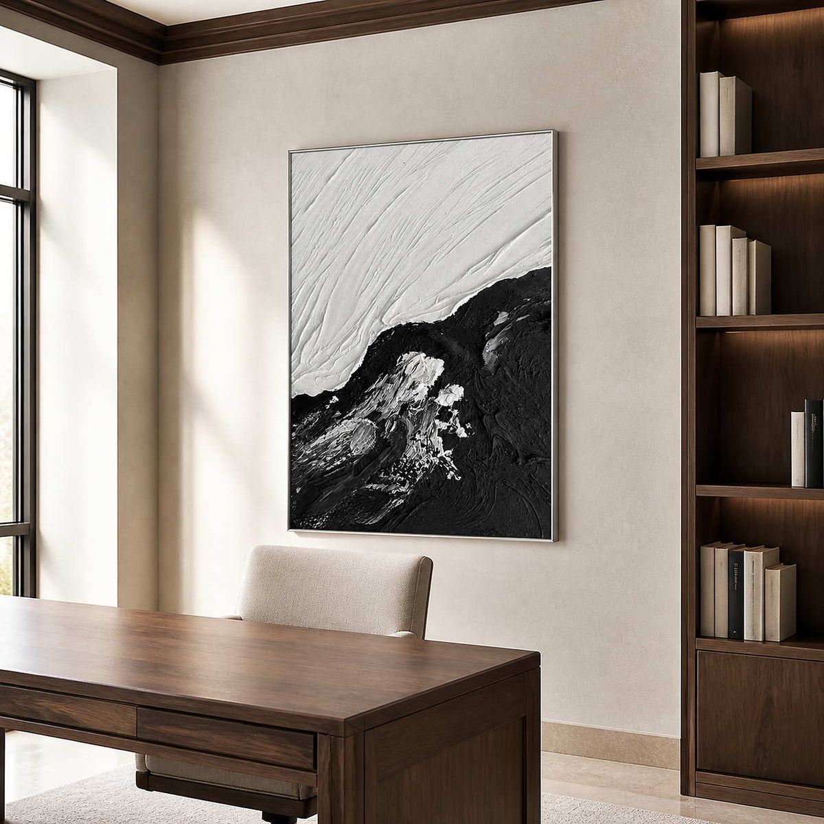 Silver framed black and white abstraction beside a wooden desk and dark bookcase.