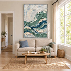 A Sea Breeze in a silver frame above a cream sofa in a bright living room with pale blue and green accents.