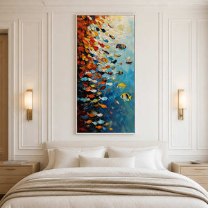 White framed colorful fish painting above a neutral bed between brass wall sconces.