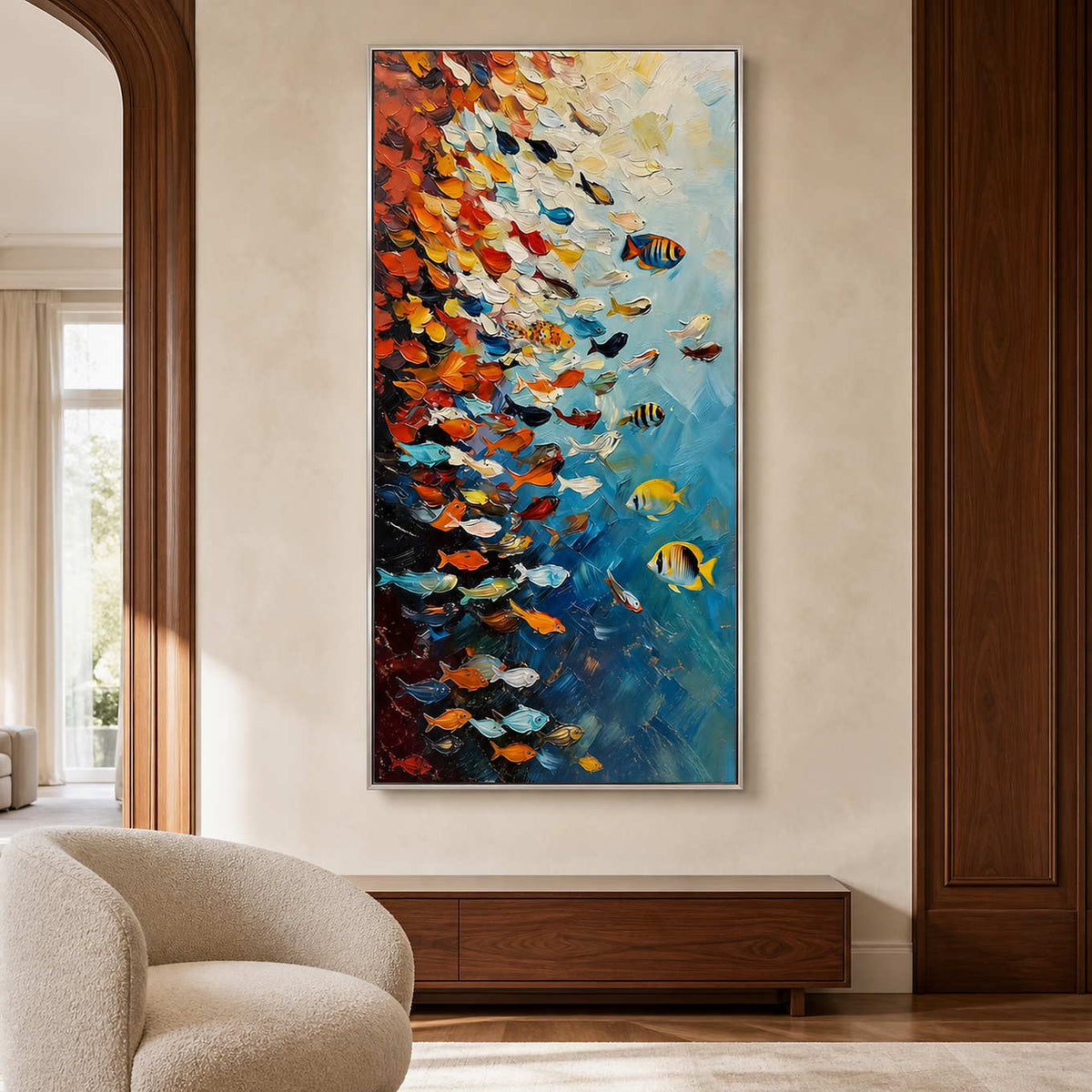 Silver framed fish artwork above a walnut console beside a rounded cream lounge chair.