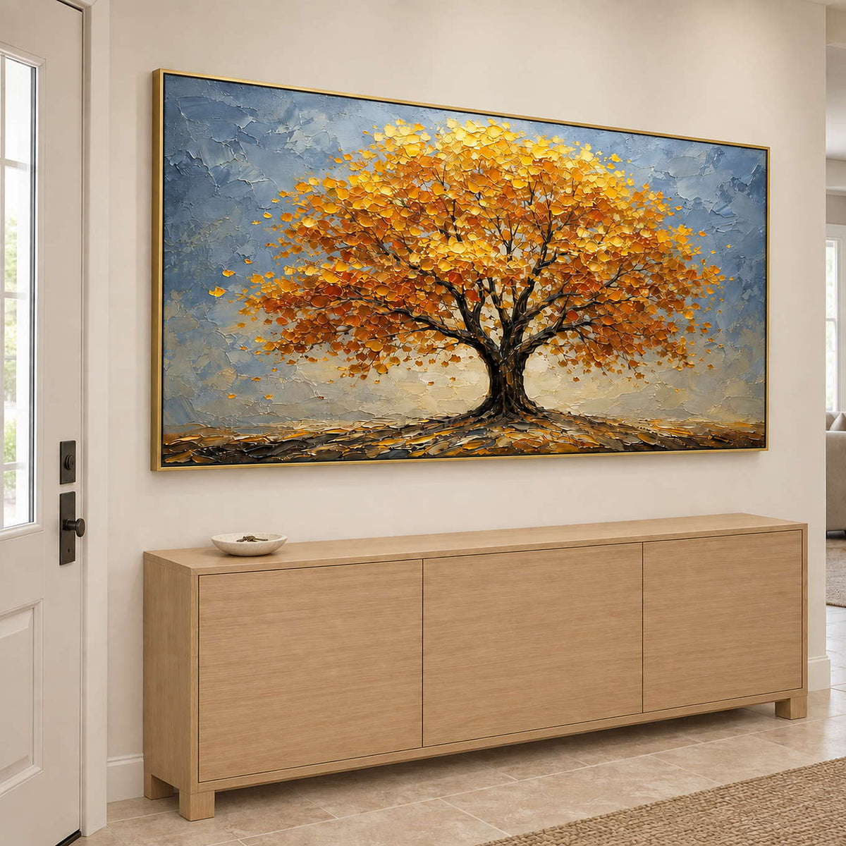 A broad golden autumn tree beneath a gray-blue sky in a gold frame, displayed above an entryway console.