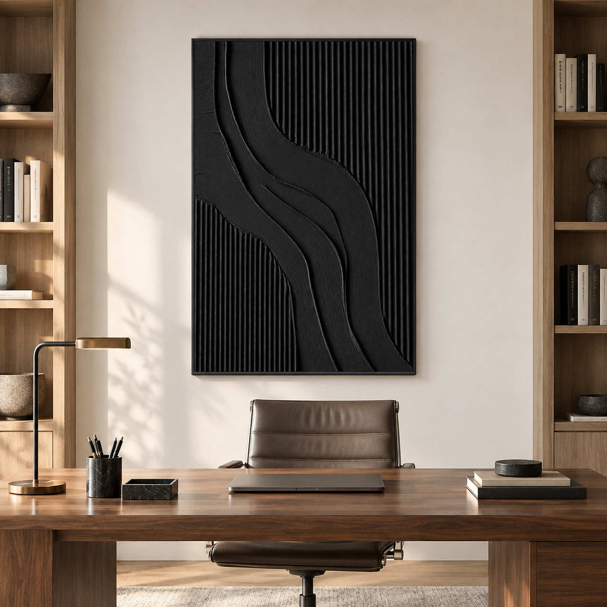 Vertical black relief-style artwork above a wooden office desk between bookshelves.