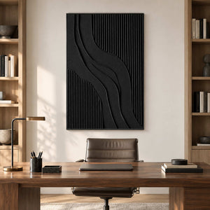 Vertical black relief-style artwork above a wooden office desk between bookshelves.