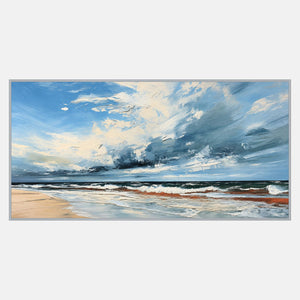 Wide coastal scene dominated by sweeping blue and cream clouds above a low horizon, white surf, and pale sand.