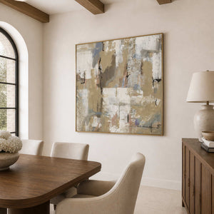 Gold-framed pale abstract artwork beside a wooden dining table with upholstered chairs and flowers.