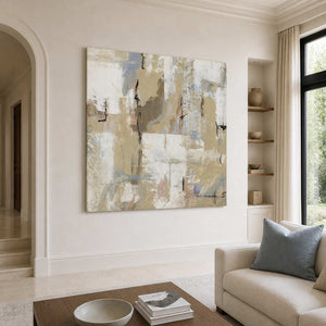 Frameless cream and blue-gray abstract artwork beside a living room sofa and recessed display shelves.