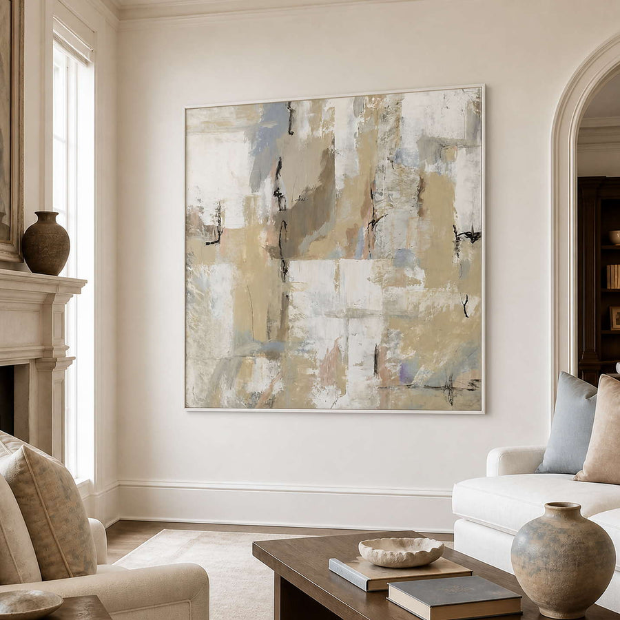 White-framed pale abstract wall art above a coffee table between cream living room seating.