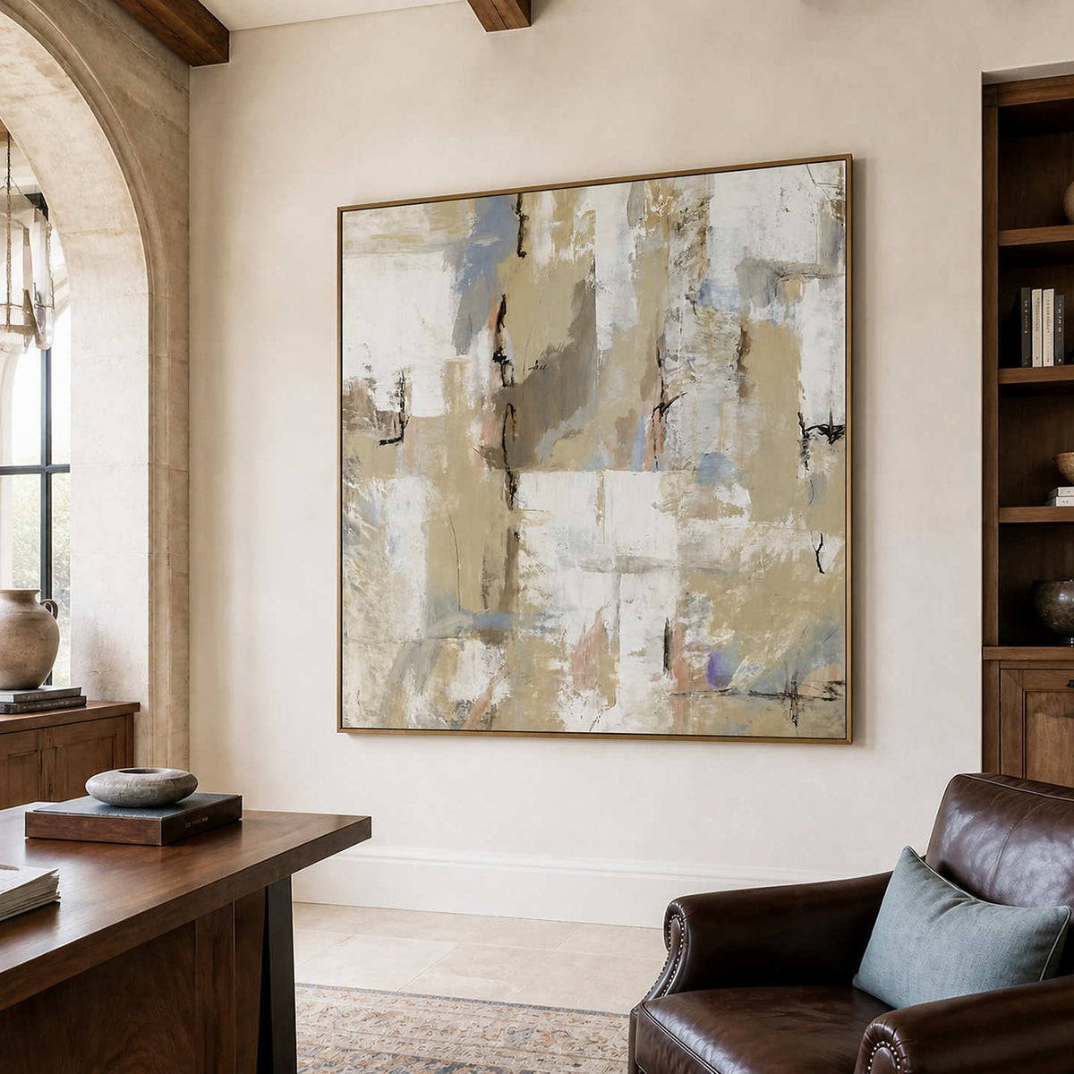 Wood-framed cream and blue-gray abstract artwork beside a desk and leather reading chair.