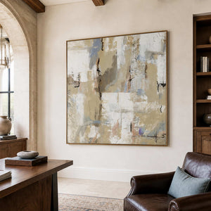 Wood-framed cream and blue-gray abstract artwork beside a desk and leather reading chair.