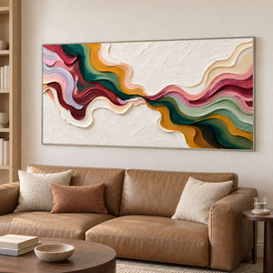 Flowing-color artwork above a tan sofa beside bookshelves.
