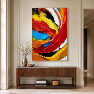 Gold framed vibrant abstract painting above a wooden console in a bright hallway.