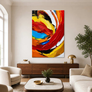 Frameless colorful swirling abstract painting above a walnut sideboard between cream seating.
