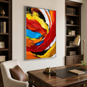 Silver framed swirling abstract painting behind a walnut desk and brown leather chair.