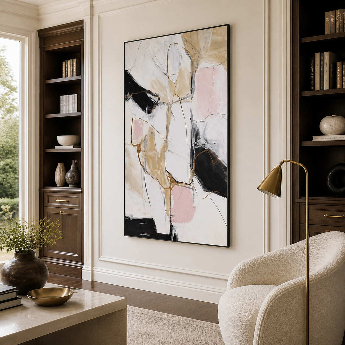 Black framed abstract artwork between dark bookshelves beside a cream reading chair.