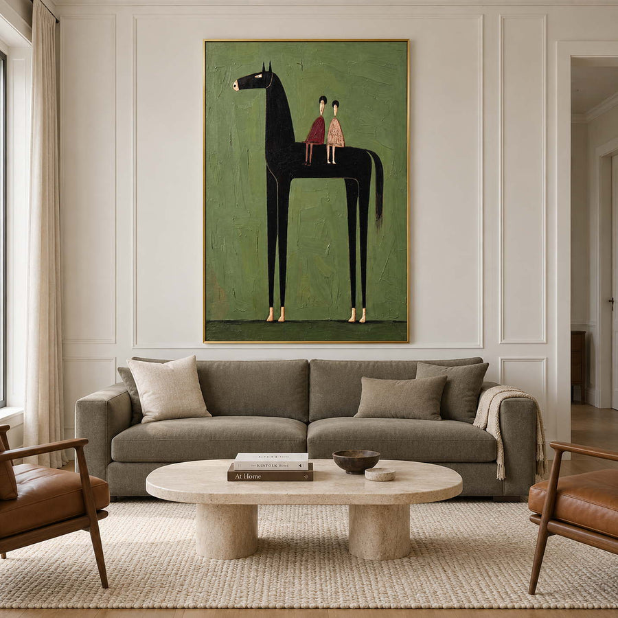 Tall black horse and two riders artwork above a muted green sofa and oval pale table.