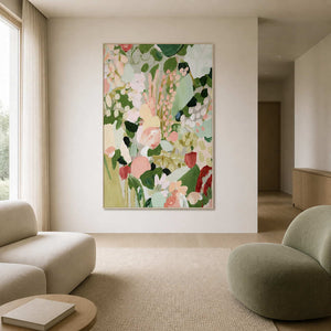 Pink and green floral painting in a white frame between soft living room seats.