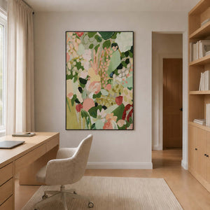 Black framed pink and green flowers beside a wood desk in a home office.