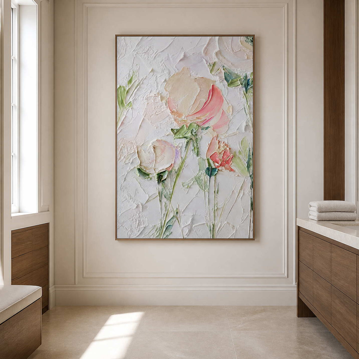 Wood framed floral artwork beside folded towels and a vanity in a bright bathroom.