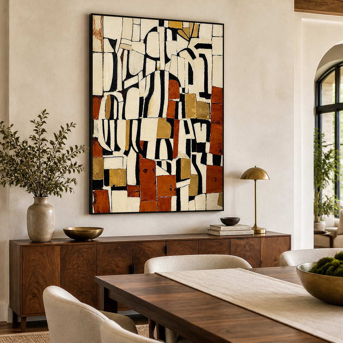 Black framed earthy geometric artwork above a sideboard beside a wooden dining table.