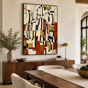 Black framed earthy geometric artwork above a sideboard beside a wooden dining table.