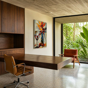 Vertical still life painting adds color to a modern home office.