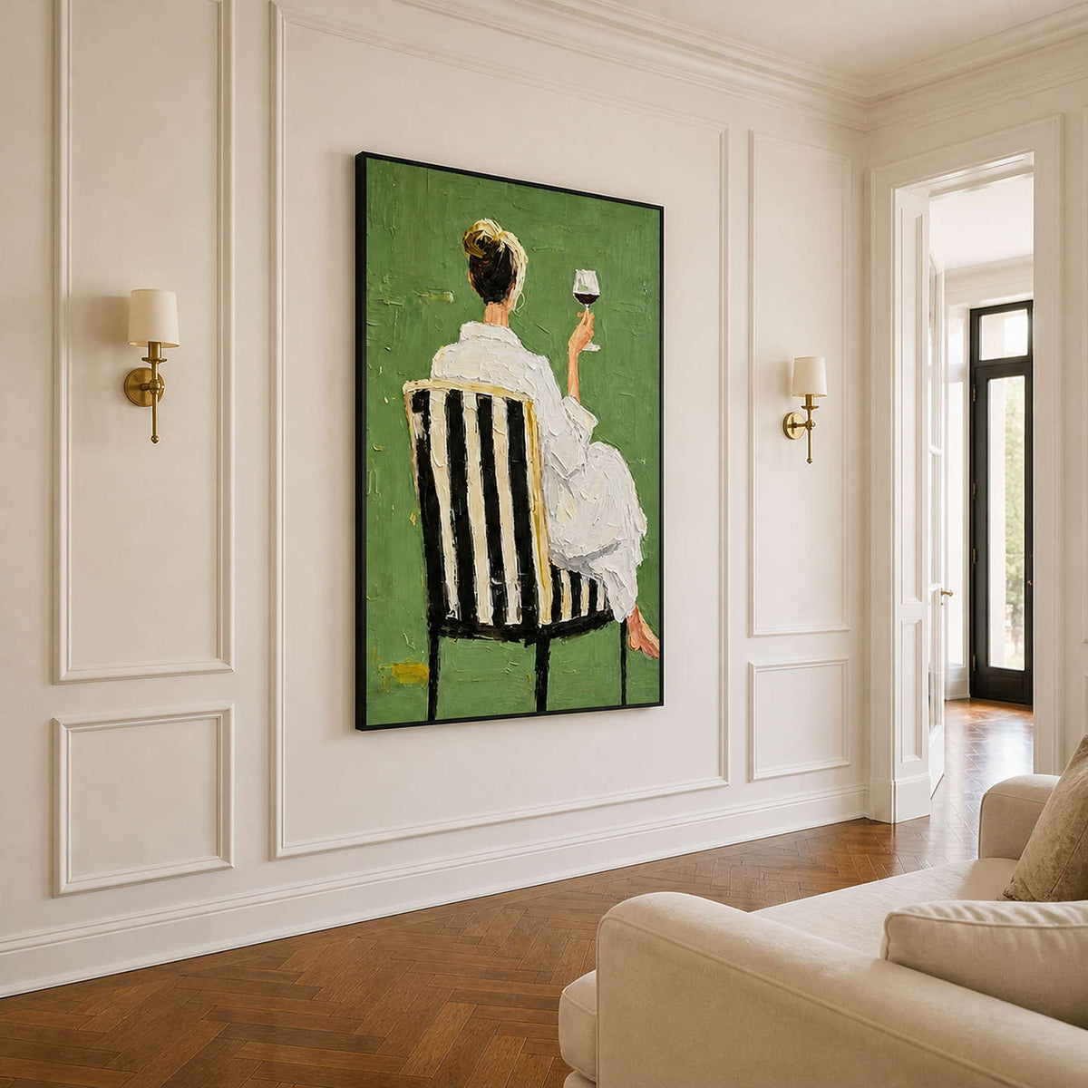 Black framed figurative painting between brass sconces beside cream seating in an ivory entrance.