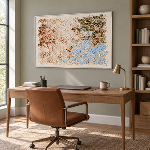 A Visit from Spring in a silver frame above a wood desk and brown leather office chair.