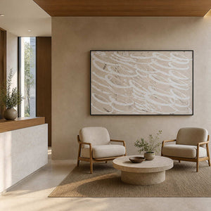 Black framed neutral abstract wall art above chairs in a hotel waiting area.