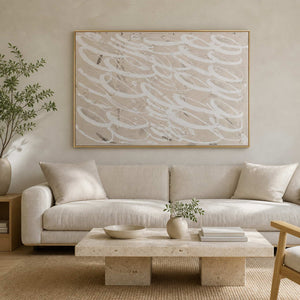 Gold framed white looping abstract art above a cream sofa and stone table.