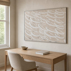 Silver framed beige and white abstract painting above a light wooden desk.