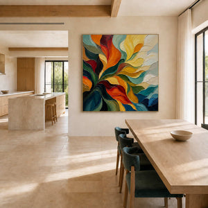 A Warm Embrace in a gold frame beside a light wood dining table in an open-plan kitchen and dining space.