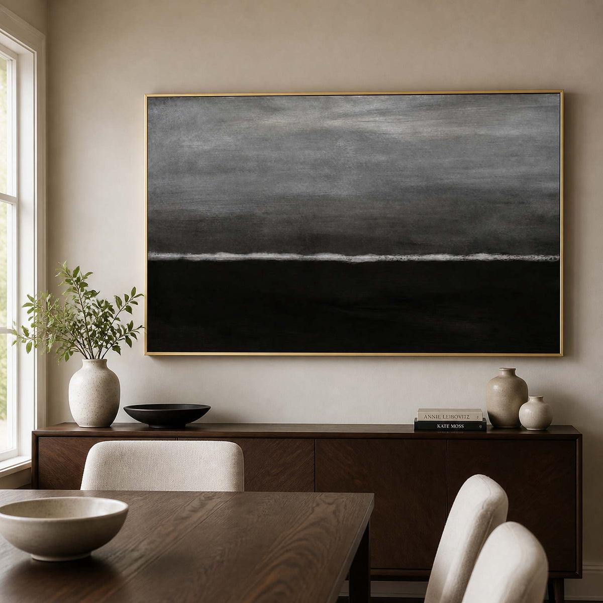 Gold framed monochrome wave painting above a dark wood sideboard in a dining room.