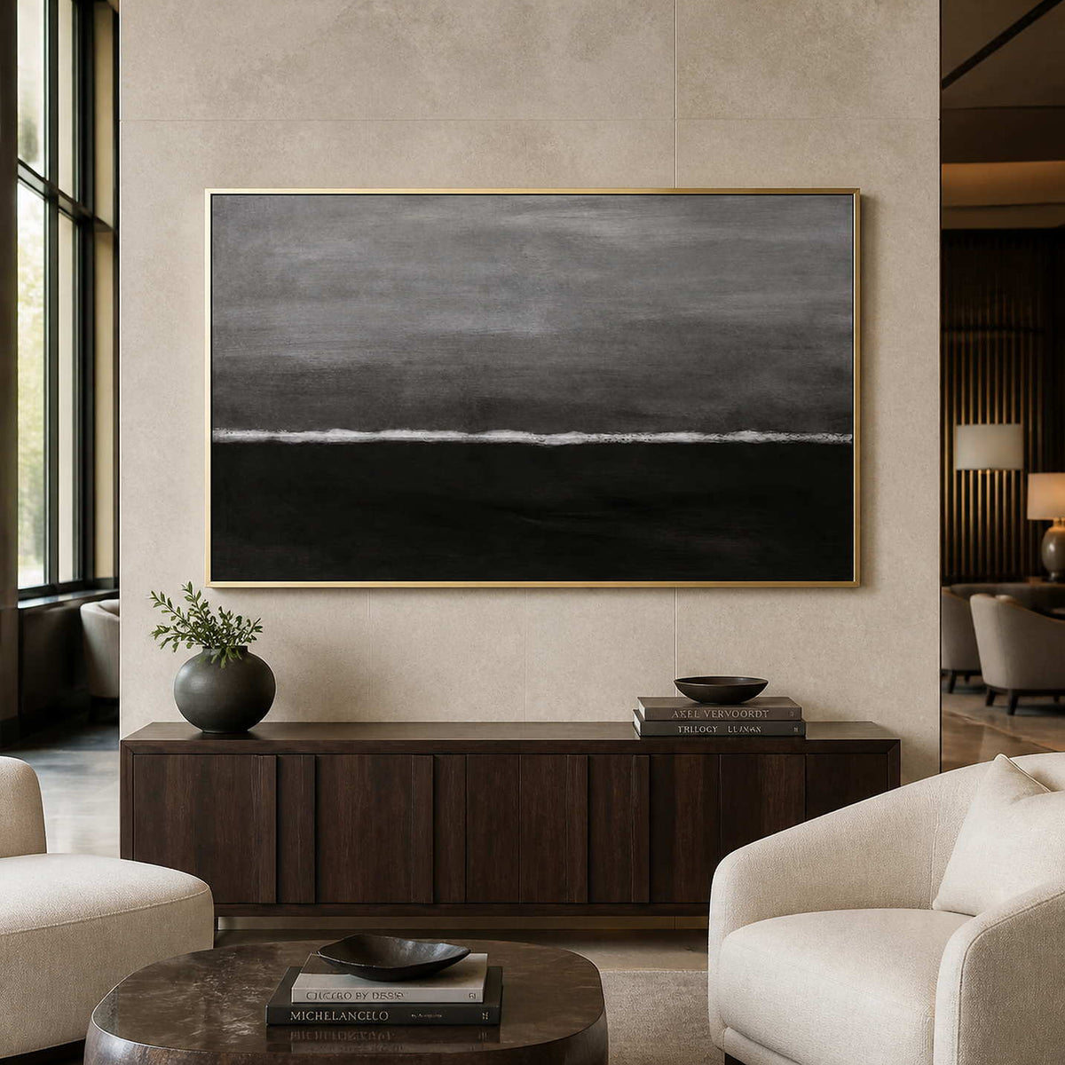 Gold framed gray horizon painting above a cabinet near hotel lobby lounge chairs.