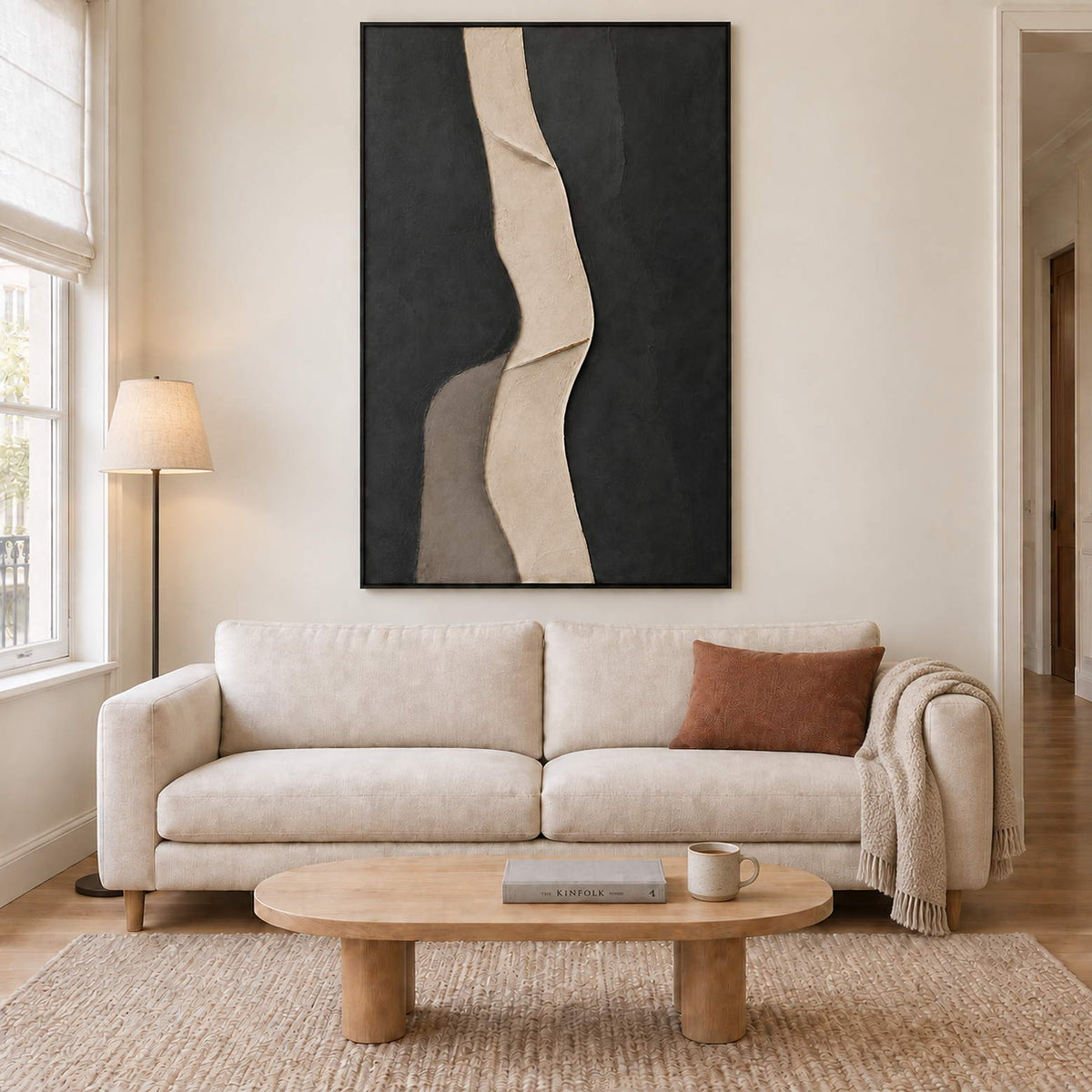 A sinuous ivory band between dark charcoal fields in a black frame, displayed above a sofa in a living room.