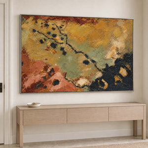 Weathered ochre, moss green and rust tones crossed by dark marks in a silver frame, displayed above an entryway console.