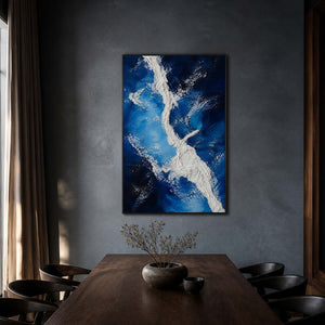 Vertical blue coastal artwork above a dark wood dining table.