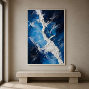 Tall blue abstract coastal art above a limestone entryway bench.