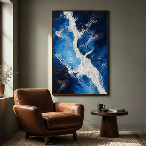 Deep blue textured artwork beside a caramel leather reading chair.