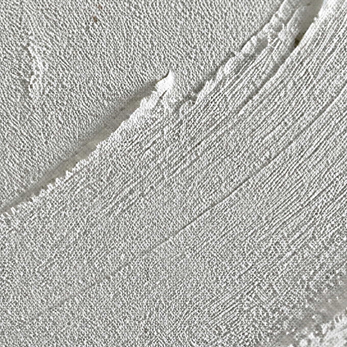 Close-up of raised white circular brushwork and finely layered canvas texture.