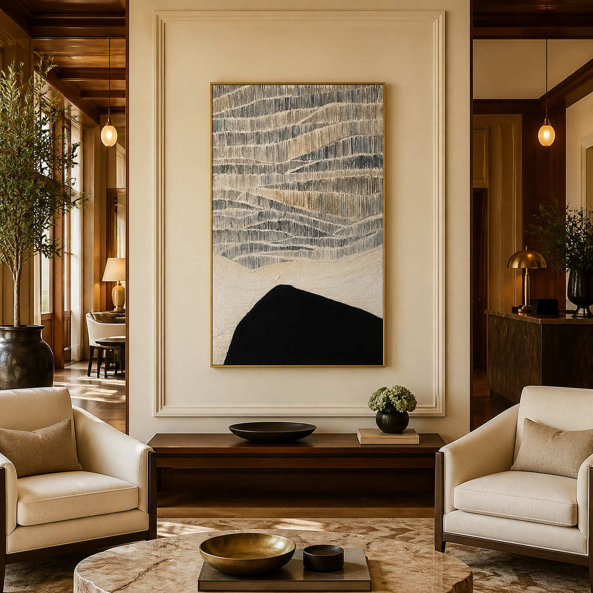 Gold framed gray and cream artwork above a console between hotel lounge chairs.