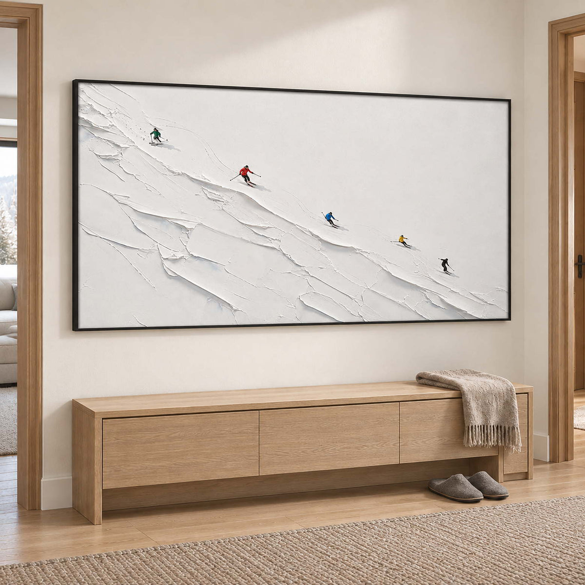 Tiny colorful skiers crossing a ridged white slope in a black frame, displayed in a hallway.