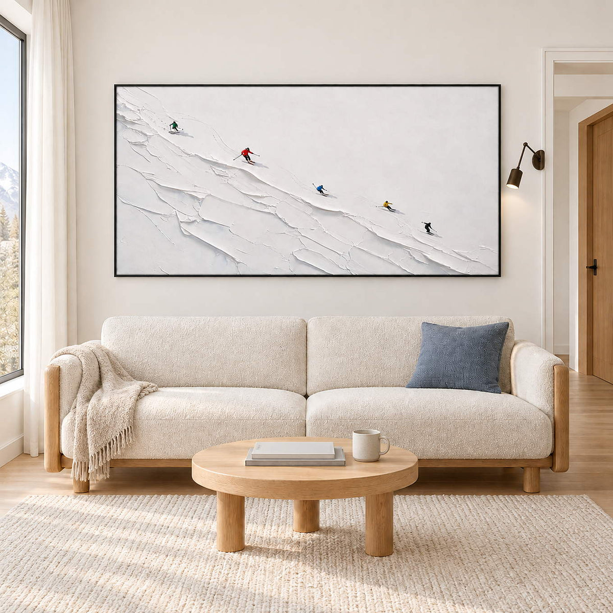 Tiny colorful skiers crossing a ridged white slope in a black frame, displayed above a sofa in a living room.