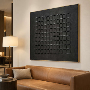 Large black geometric painting above a tan leather sofa beside a shaded floor lamp.