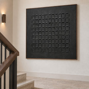 Angled view of the black grid artwork on a pale stairwell wall.
