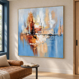 Artwork showing amber and rust blocks crossing a dark horizontal line on pale blue beside a reading chair, with a gold-colored frame.