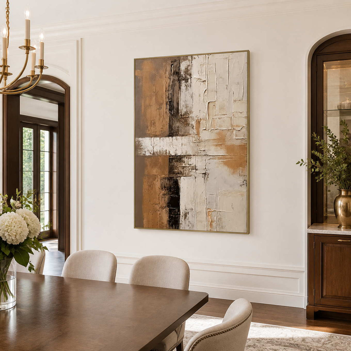 Gold-framed abstract wall art above a wooden dining table with cream chairs.